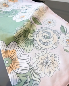 Detailed view of floral satin scarf texture with elegant pink and green botanical prints