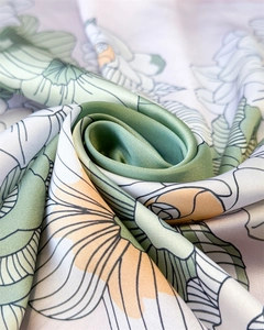 Macro shot of elegant floral silk scarf with green leaves and orange blossoms