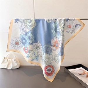 Close-up of floral print silk scarf with gradient blue background and orange edges