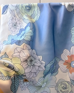 Macro detail of silk square scarf featuring blue floral prints and artistic rose patterns