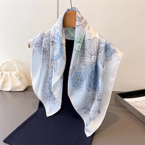 Detailed view of floral silk scarf with blue roses draped over a black garment