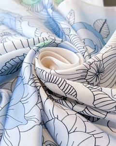 Detailed macro view of floral print silk scarf with light blue and green petal patterns