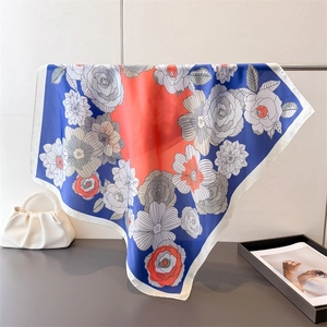 Detail of elegant navy blue and orange floral print on a square silk-like satin scarf