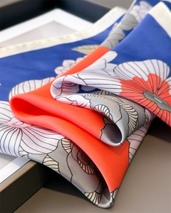 Detail of floral silk scarf showing premium texture and rolled edges in royal blue
