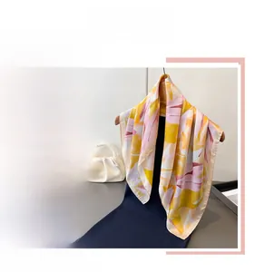 Détail d'un foulard en soie aux motifs floraux abstraits dans les tons jaune et rose