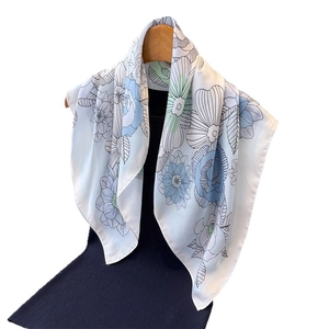 Elegant white floral silk scarf with blue patterns draped on a wooden hanger stylishly