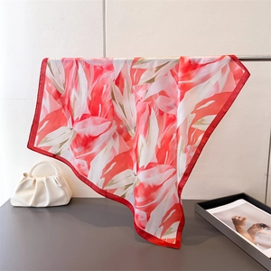 Détail d'un foulard en soie rouge et blanc drapé avec un sac à main à perles