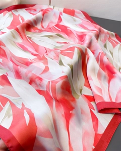 Détail d'un foulard en soie aux motifs floraux rouges et texture fluide et satinée