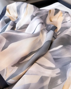 Gros plan d'un foulard en satin soyeux avec motifs floraux gris et texture plissée douce