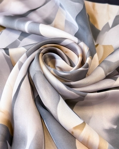 Vue détaillée de la texture soyeuse et de l'imprimé géométrique abstrait du foulard en soie