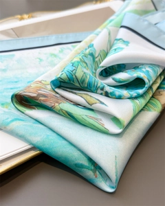 Detail of floral silk scarf showing mint green leaf patterns and smooth satin texture