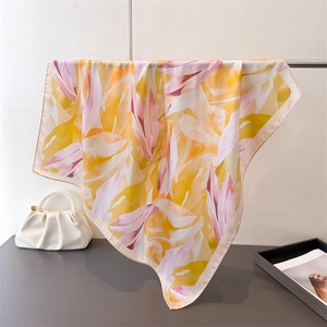 Détail d'un foulard en soie rose et jaune drapé avec élégance avec un sac à main perle