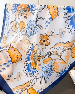 Detail of floral printed silk scarf showing smooth texture and vibrant orange-blue patterns