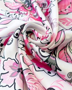 Macro view of silky floral print fabric with vibrant pink patterns and smooth satin texture