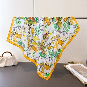 Detail of floral printed silk square scarf with yellow borders hanging on a metal stand