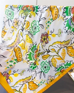 Detail of silk square scarf featuring tropical floral prints and yellow borders