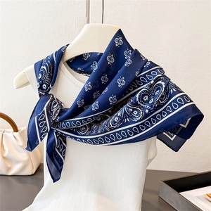 Navy blue silk square scarf with classic white paisley pattern around a woman's neck