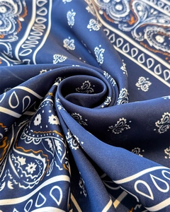 Macro shot of navy blue silk scarf with white paisley pattern folded in a spiral shape