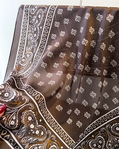 Macro detail of the brown paisley print on the lightweight silky scarf for women