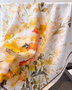 Close-up of floral silk scarf with yellow and orange patterns and dark hemmed edges