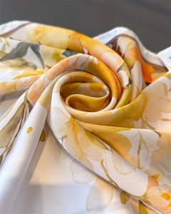 Detailed close-up of floral silk scarf with vibrant orange and yellow watercolor pattern