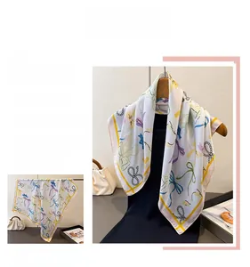 Close-up of elegant silk scarf featuring colorful ribbon prints and pearl motifs on a hanger