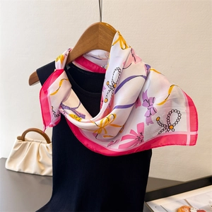 Detail of silk-feel scarf with bow and pearl prints tied on a black sleeveless top