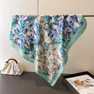 Foulard en satin à imprimé floral avec bordure vert menthe sur un support élégant