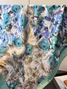 Détail d'un foulard en soie à fleurs avec bordure en satin vert et drapé élégant
