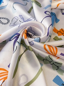 Detailed close-up of silky satin fabric with colorful ribbon and bow print patterns