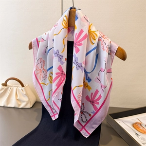 Elegant white satin square scarf with colorful bow prints on a wooden hanger
