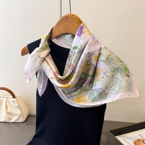 Dettaglio del foulard in seta rosa a fiori appeso su top nero con gruccia in legno