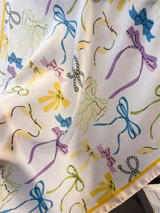 Detailed view of silk-like scarf with colorful bow ties and pearl necklace patterns