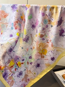 Dettaglio di un foulard in seta a fiori con bordi gialli e motivo artistico dipinto a mano