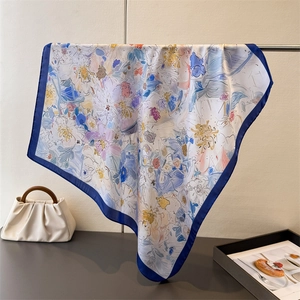 Dettaglio di un foulard di seta quadrato con stampe floreali astratte e bordi blu navy
