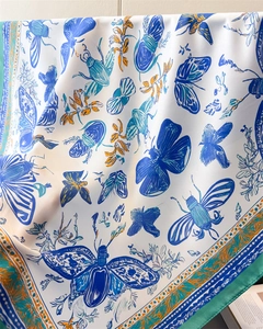 Detailed close-up of French silk scarf featuring butterfly prints and green satin edges