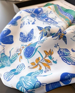 Detail of silk-like satin scarf with butterfly prints in blue and orange on a magazine