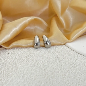 Sleek silver teardrop stud earrings with polished mirror finish on white textured surface