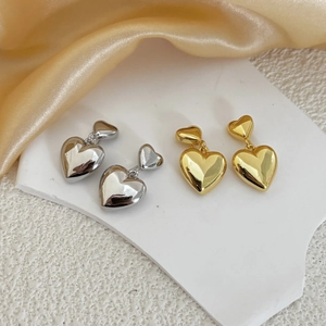 Boucles d'oreilles pendantes en forme de cœur dorées et argentées sur soie blanche élégante