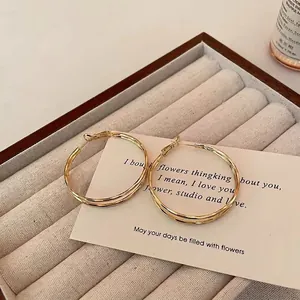 Detail of elegant gold double-hoop earrings displayed on a beige velvet jewelry box