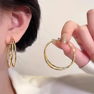 Double-layered gold circular earrings with hammered metal texture for a minimalist style