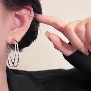 Close-up of elegant double-layered silver hoop earrings worn by a model for size