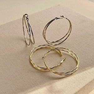 Detail of double-layer hoop earrings showing gold and silver textured metal surfaces