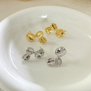 Detailed close-up of organic petal earrings in polished gold and silver metal finishes