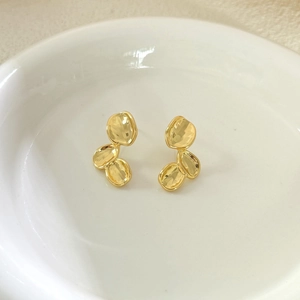 Minimalist gold irregular petal stud earrings with textured finish in ceramic dish