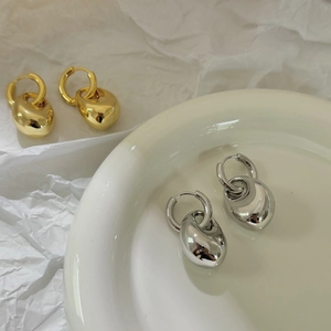 Détail de boucles d'oreilles en forme de goutte en or et argent au lustre métallique lisse