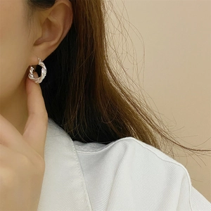 Close-up of silver twist rope hoop earrings worn on ear with minimalist style