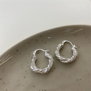 Close-up of silver twist textured hoop earrings with sparkling geometric facets detail