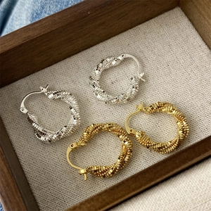 Close-up of gold and silver twisted hoop earrings with textured spiral design