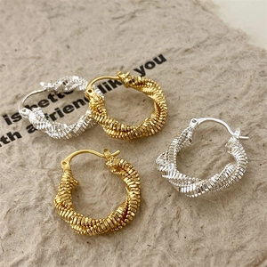 Detailed view of gold and silver twisted spiral hoop earrings on a textured paper background